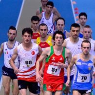 A group of runners with intellectual impairments race on an indoor track